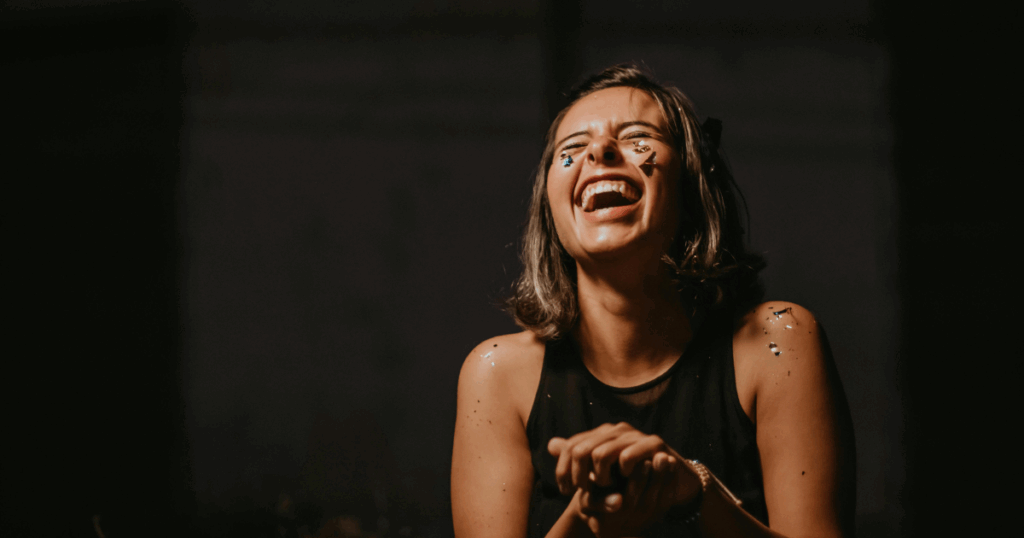 Woman laughing joyfully, showcasing the benefits of laughter for wellness and health. Embracing a happy, positive lifestyle.