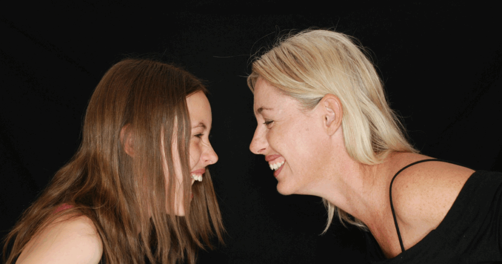 Mother and daughter laughing together, showcasing the joy and wellness benefits of laughter, promoting positive emotions.