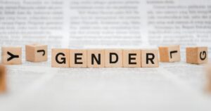 - Treat Mental Health Washington Wooden letter blocks spell 'GENDER' on a blurred newspaper backdrop to symbolize gender topics.