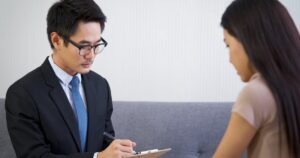 - Treat Mental Health Washington Professional man in a dark suit and blue tie writes on a clipboard during a client consultation.