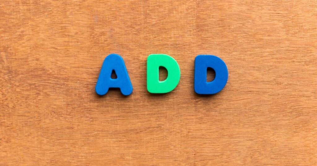 Foam letters spell 'ADD' in blue-green-blue on a wooden surface